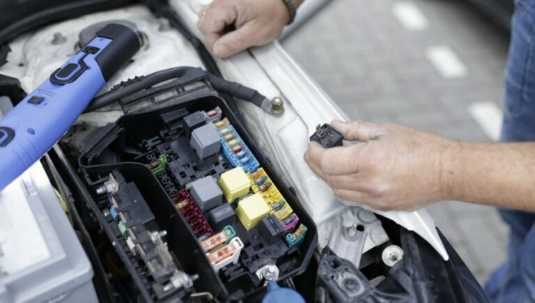 Возач проверува автомобилски акумулатор во гаража