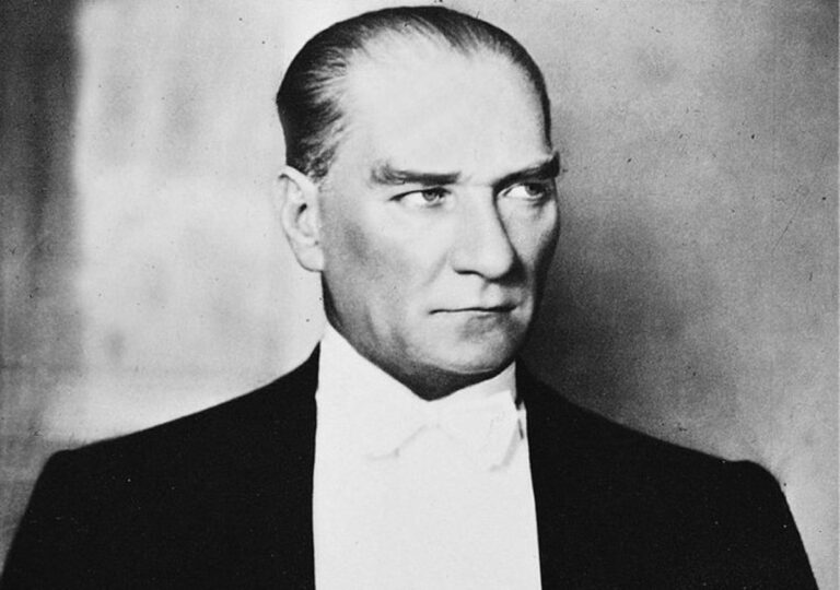 Мустафа Кемал Ататурк во 1930-тите години, фотографиран во темен фрак со бела вратоврска — претседател на Република Турција и симбол на нејзината модернизација.