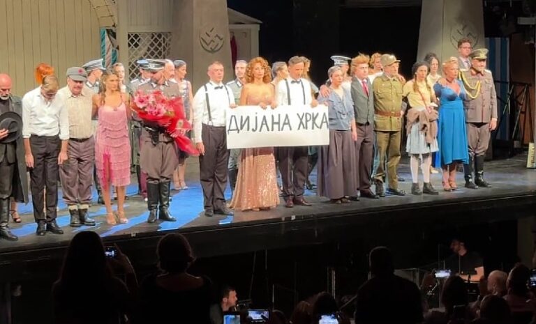 Актерите од Народниот театар во Белград држат транспарент со порака на сочувство